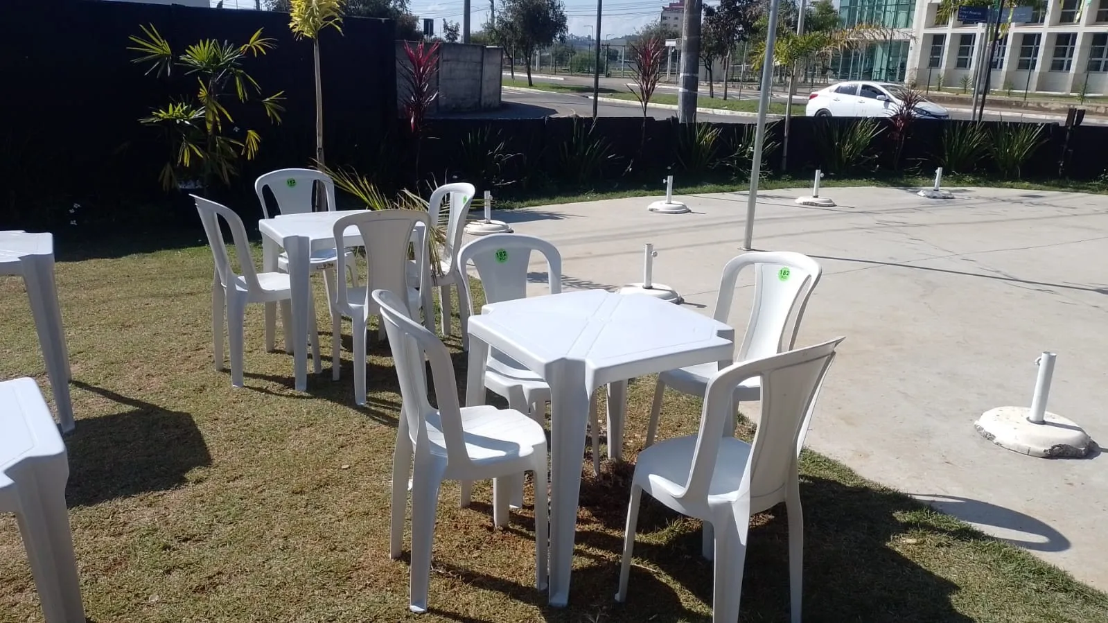 Mesas e cadeiras plásticas montadas em área externa com gramado